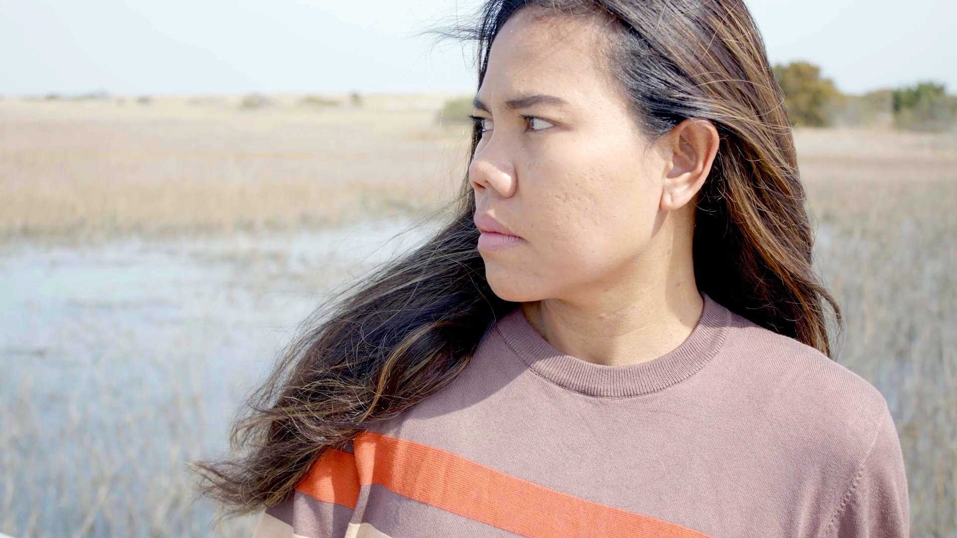 A woman stairs stands in front of a salt water marsh